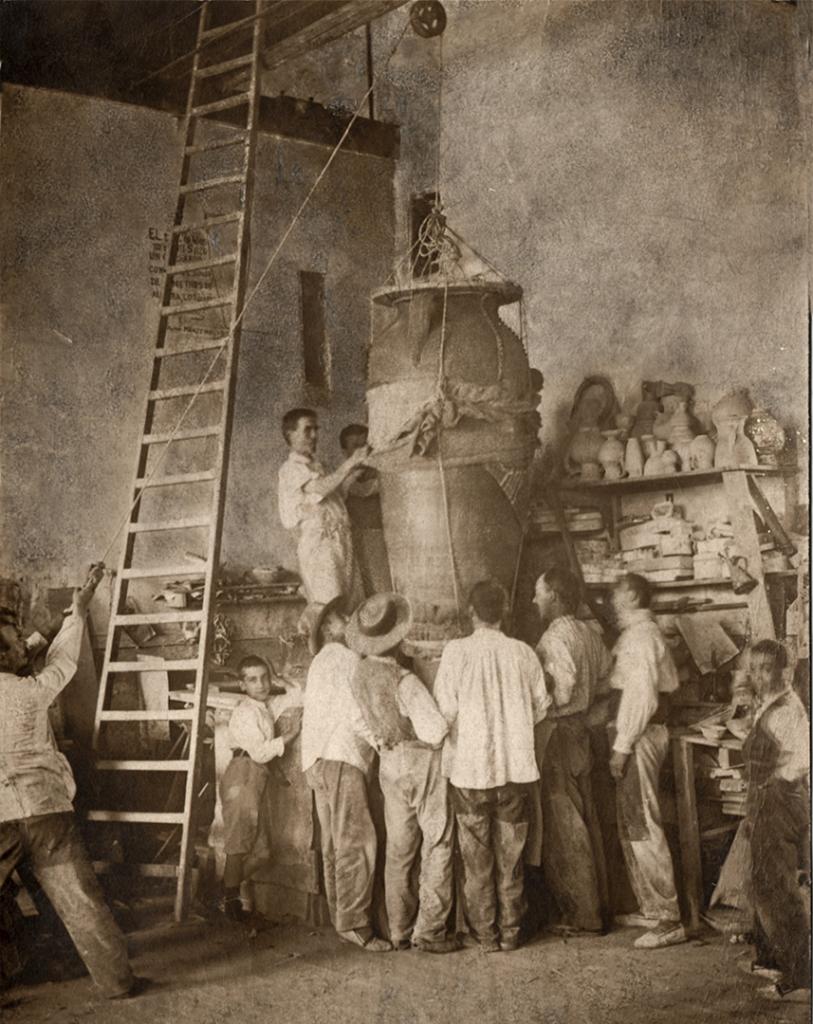 Una tinaja, de gran tamaño, es izada a cuerda ante los operarios